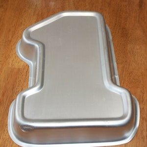 May include: Silver-colored metal cake pan shaped like the number one.