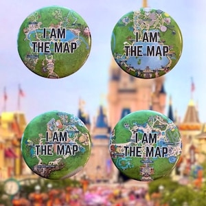 May include: Four circular pin-back buttons featuring colorful theme park map illustrations. Each button displays the text I AM THE MAP in bold black capital letters centered over a detailed green and blue park layout design.