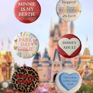 May include: Six circular pinback buttons featuring various designs: a red button with white text reading MINNIE IS MY BESTIE, a white button with text reading Happiest Birthday On Earth, a multi-colored button with PARK DAY GIRLIE, a red heart button with DISNEY ADULT, a leopard print button with red text reading Disney Adult, and a white heart button with blue text reading CRIES DURING HAPPILY EVER AFTER.