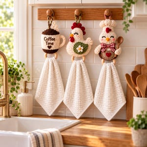May include: Three crocheted hanging kitchen towels featuring decorative toppers: a brown coffee mug with the text Coffee Time, a white chicken with a green wing and flower, and a white chicken chef wearing a hat and holding a wooden spoon.