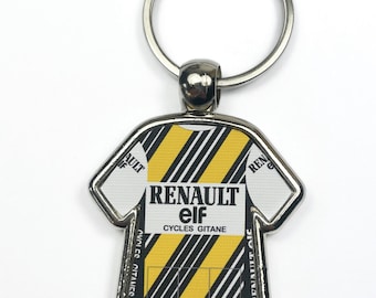 May include: A metal keychain featuring a jersey design with the Renault Elf Cycles Gitane logo. The jersey has a yellow and black striped pattern with white accents and a silver key ring.