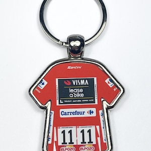 May include: Red jersey-shaped keychain with a silver border and ring. The jersey features sponsor logos, including "VISMA lease a bike" and "Carrefour." The number "11 11" is displayed prominently. The keychain is a cycling-themed accessory.