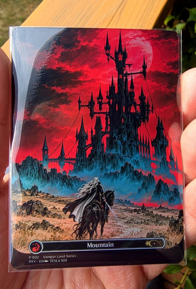 May include: A rectangular trading card featuring a dark castle silhouette against a vibrant red sky. A figure with long white hair rides a black horse in the foreground. The card displays the text Mountain, P 002 Vampyr Land Series, PXY-EN TESLA XIII.