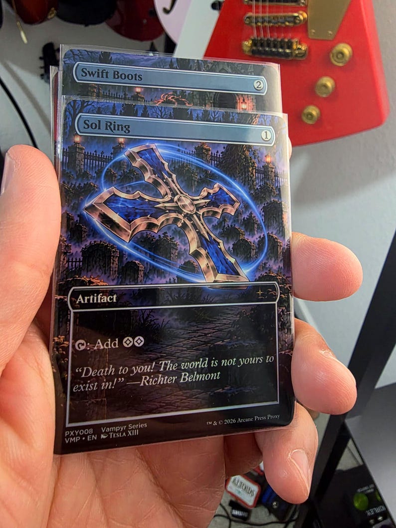 Puede incluir: Una carta coleccionable rectangular titulada Sol Ring con un icono de cruz azul brillante sobre una escena de cementerio. El texto incluye Artifact, Add dos man&aacute;s incoloros y una cita de Richter Belmont. Una segunda carta, Swift Boots, se ve detr&aacute;s.