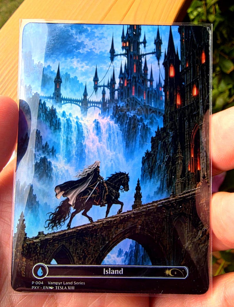 May include: A rectangular trading card titled Island from the Vampyr Land Series, featuring a rider on a black horse crossing a stone bridge toward a dark gothic castle with glowing red windows, set against a backdrop of blue waterfalls.