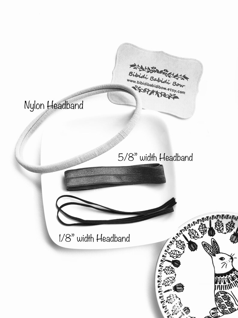 Op de afbeelding: Drie haarbanden in verschillende breedtes: een witte nylon haarband, een grijze haarband van 1,6 cm breed en een zwarte haarband van 0,3 cm breed. De tekst "Bibidi Babidi Bow" en "www.bibidibabidibow.etsy.com" staat gedrukt op een wit label.