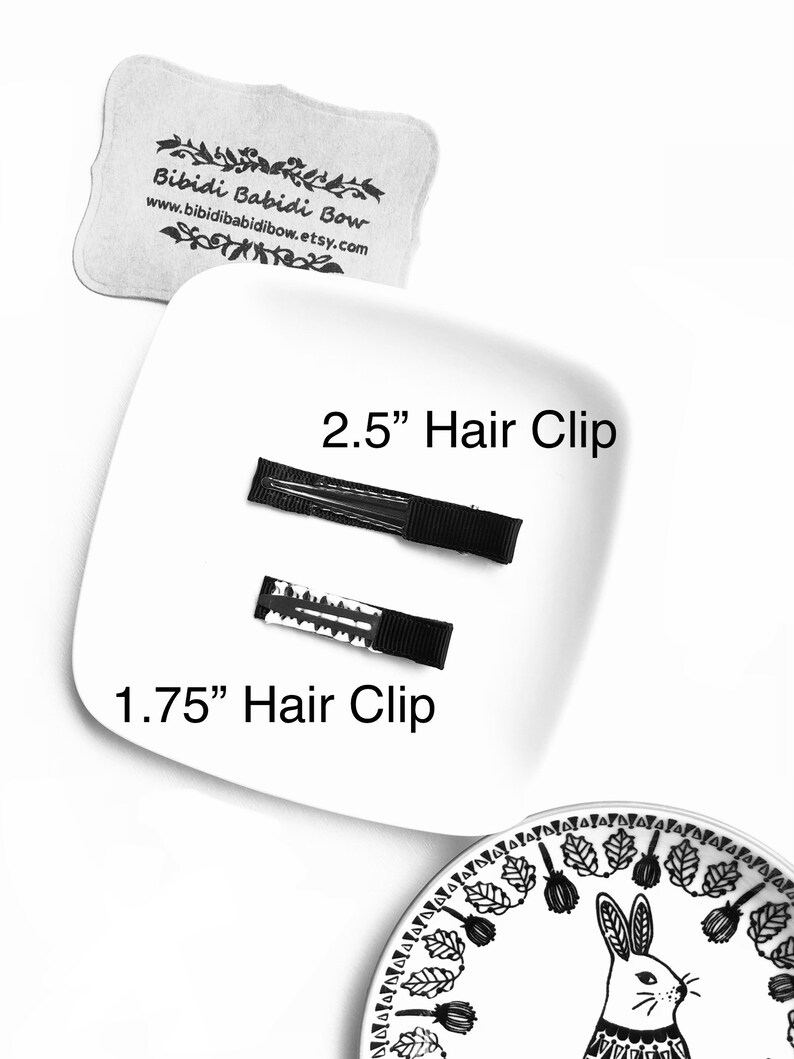Op de afbeelding: Twee zwarte haarclips op een wit bord. De grotere clip is 2,5 inch lang en de kleinere clip is 1,75 inch lang.