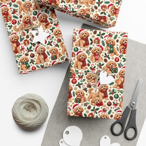 May include: Wrapping paper featuring a repeating pattern of golden-brown puppies wearing red or green scarves and Santa hats, interspersed with Christmas ornaments, candy canes, pine sprigs, and gift boxes on a cream-colored background.