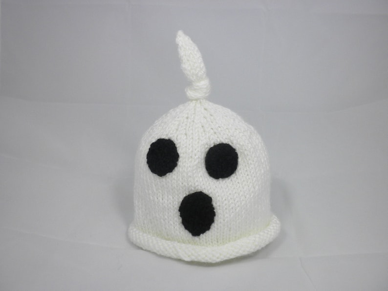 Puede incluir: Un gorro de fantasma blanco tejido con tres rasgos faciales negros: dos ojos redondos y una boca ovalada grande. El gorro tiene una parte superior anudada y un borde acanalado. Este gorro con tem&aacute;tica de Halloween es perfecto para disfraces.