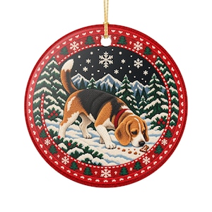 Könnte beinhalten: Ein rundes Keramikornament mit einem Beagle, der an einem Leckerli in einer verschneiten Landschaft mit Tannen und Bergen schnüffelt. Der Rand hat ein rot-weiß-grünes Strickmuster mit Schneeflocken und eine goldene Aufhängeschnur.