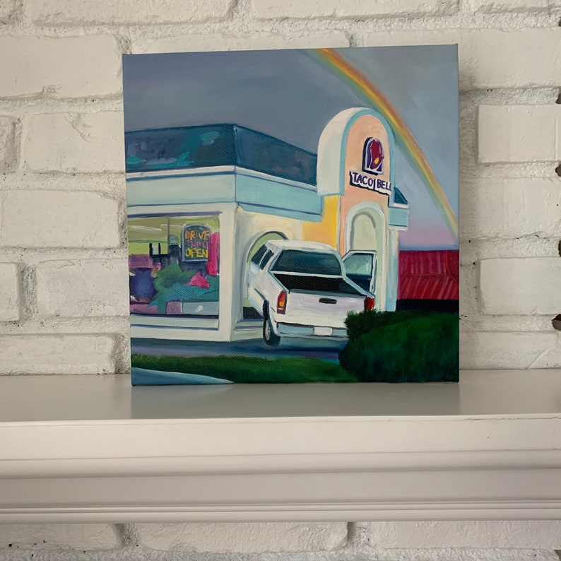 May include: A painting of a Taco Bell restaurant with a rainbow in the sky. A white pickup truck is parked in the drive-thru lane with the words "Drive Thru Open" on the window.