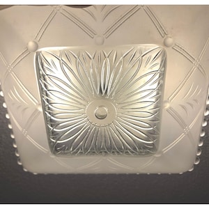 May include: A square glass ceiling light fixture featuring a frosted finish with a clear, pressed glass center panel. The center displays a radiating sunburst or floral pattern, while the surrounding frosted border has a grid design.