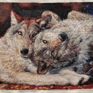 May include: A cross-stitch embroidery of two white wolves cuddling together. The wolves are depicted in a realistic style with detailed fur and facial features.