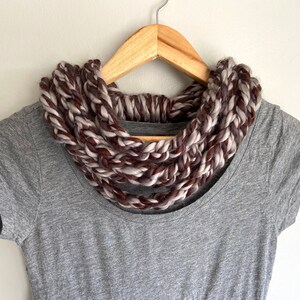 This chunky brown and gray scarf necklace is made of many layers of crochet chains by designer DottieQ. Wear it gathered and sleek like an infinity scarf, or twisted for a layered chain look.