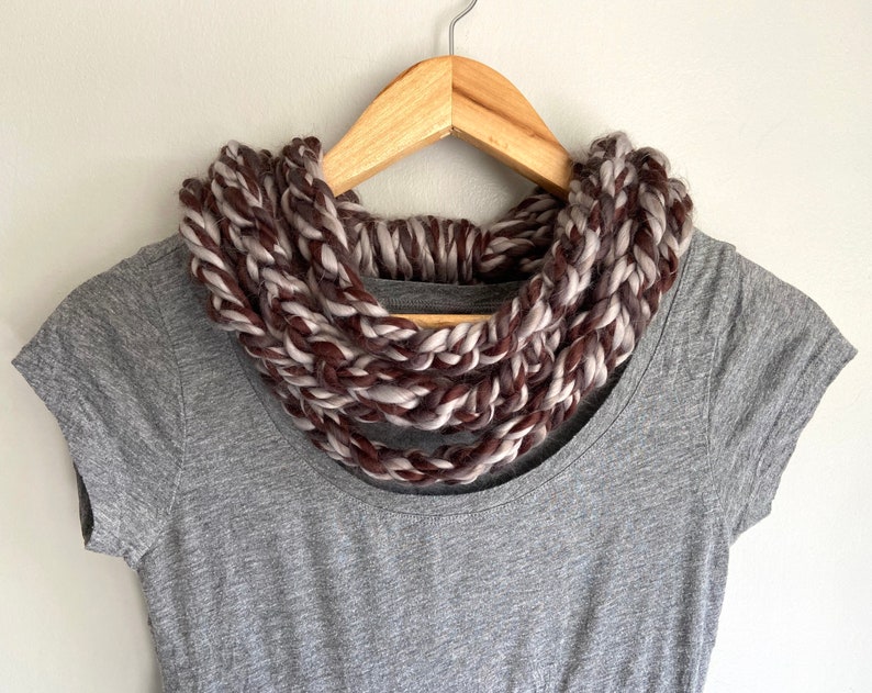 This chunky brown and gray scarf necklace is made of many layers of crochet chains by designer DottieQ. Wear it gathered and sleek like an infinity scarf, or twisted for a layered chain look.