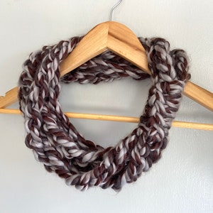 This chunky brown and gray scarf necklace is made of many layers of crochet chains by designer DottieQ. Each chain is secured with a signature knot, which is wrapped around a 2-3 inch area  with a crochet detail up the middle.