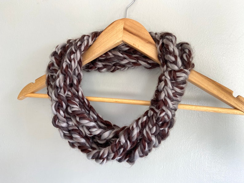 This chunky brown and gray scarf necklace is made of many layers of crochet chains by designer DottieQ. Each chain is secured with a signature knot, which is wrapped around a 2-3 inch area  with a crochet detail up the middle.