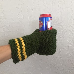 This beer mitten is green with yellow stripes around the wrist. It is part crochet can holder part mitten. A hand is in it and a can of beer inside the holder. The bottom is covered so the can stays in place. It can be used on either hand.
