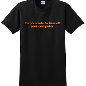 May include: Black t-shirt with the text "It's now safe to turn off your computer." in orange.