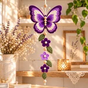 May include: A hanging crochet decoration featuring a large purple and cream butterfly at the top, followed by a vertical string of alternating wooden beads, green crocheted leaves, and purple crocheted flowers with small white pearl centers.