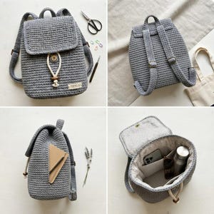 May include: A grey crocheted backpack featuring a flap closure with a white drawstring, a wooden bead accent, and a small rectangular label. The interior is lined with light fabric and includes pockets containing a smartphone, sunglasses, and a bottle.