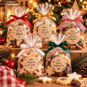 Puede incluir: Cinco bolsas de celofán transparente rellenas de galletas navideñas variadas, cada una atada con una cinta de color y con una etiqueta redonda de papel kraft con texto en alemán, incluyendo frases como Eine Portion Glück.