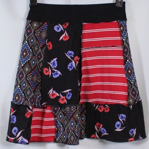 Peut inclure: Une jupe noire avec un motif patchwork composé de rayures rouges, bleues et blanches, de motifs floraux et de formes géométriques.