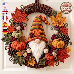 May include: A crochet autumn wreath featuring a central gnome with a striped hat, white beard, and round nose. The wreath is decorated with crocheted maple leaves in red, orange, and yellow, small pumpkins, acorns, pinecones, and red berry clusters.