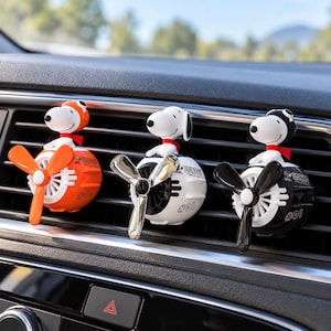 Può includere: Tre deodoranti per auto con figure di Snoopy che indossano cuffie da aviatore e sciarpe rosse. Ogni figura poggia su una base sferica con un'elica rotante. Le basi sono arancioni, bianche e nere, contrassegnate con la scritta Snoopy e #01.