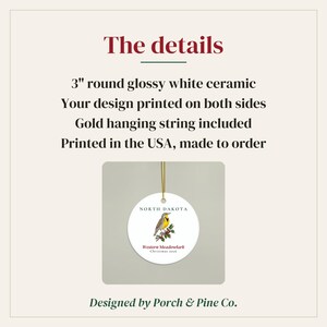 Peut inclure: Une d&eacute;coration en c&eacute;ramique blanche brillante et ronde de 7,62 cm avec une illustration de sturnelle des pr&eacute;s, le texte NORTH DAKOTA et Western Meadowlark Christmas 2026. Elle inclut un cordon dor&eacute; et est imprim&eacute;e sur les deux faces.