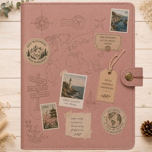 Puede incluir: Un diario de viaje color rosa empolvado con un estampado de mapa mundial, una rosa de los vientos y varias pegatinas de temática viajera, incluyendo sellos de Italia y Japón, una foto de un faro y una etiqueta Notes Memories Adventures.