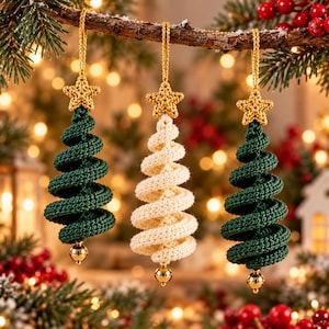 May include: Three hanging ornaments shaped like spiral Christmas trees. Two are dark green and one is cream-colored. Each tree is topped with a small crocheted gold star and features a gold cord loop for hanging, with a shiny gold bead at the base.