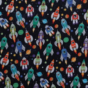 May include: A black fabric with a repeating pattern of colorful rockets and planets. The rockets are various shades of blue, green, red, and orange. The planets are various shades of blue, green, and orange.