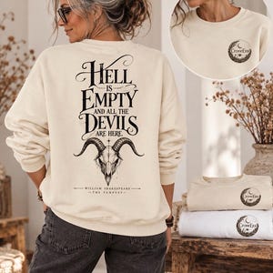 May include: A cream-coloured crewneck sweatshirt featuring a black graphic on the back with the text "Hell is empty and all the devils are here" above a goat skull illustration and "William Shakespeare - The Tempest" below. A small logo is on the front.