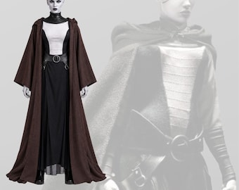 May include: A full-length costume featuring a brown hooded robe with wide sleeves, worn over a white sleeveless top and a long black skirt. A black belt with a circular buckle cinches the waist, and a black high-neck collar piece completes the outfit.