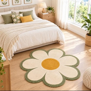 May include: A flower-shaped area rug featuring a central circular mustard yellow tufted section surrounded by eight cream-colored petals, all outlined with a textured olive green border. The rug has a soft, plush pile and a distinct floral silhouette.