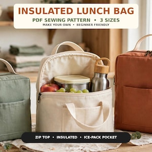 Op de afbeelding: Drie geïsoleerde lunchtassen in olijfgroen, crème en terracotta oranje. De tassen hebben een ritssluiting, een voorvak en een handvat. De crèmekleurige tas staat open en bevat een metalen bakje, een rode appel, groene druiven en een drinkfles.