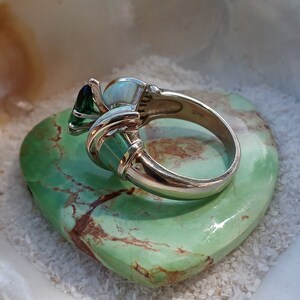 May include: A silver ring with a green gemstone, a white opal, and a green stone set in a silver band.