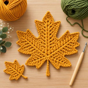 Peut inclure: Une grande et une petite feuille d'érable au crochet en fil jaune moutarde. Les feuilles présentent un motif de points texturé avec des nervures définies. À proximité se trouvent une pelote de fil jaune moutarde, une pelote de fil vert olive et un crochet en bois.
