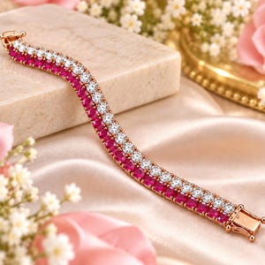Pode incluir: Uma pulseira de ténis de fila dupla com uma linha de pedras redondas cor-de-rosa vibrantes ao lado de uma linha paralela de pedras brancas transparentes, montadas numa banda de metal em tom de ouro rosa com um fecho de caixa.