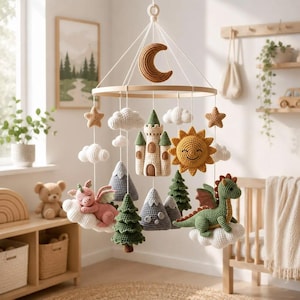 May include: A nursery mobile featuring crocheted figures suspended from a circular wooden frame. The hanging elements include a brown crescent moon, white clouds, a beige castle, a yellow sun, green pine trees, gray mountains, and two dragons.