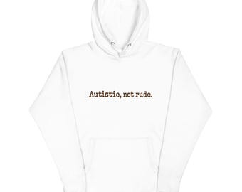 Könnte beinhalten: Ein weißer Kapuzenpullover mit langen Ärmeln, einer Kängurutasche auf der Vorderseite und einer Kapuze mit Kordelzug. Der Text 'Autistic, not rude.' ist in einer dunkelbraunen, strukturierten Schrift mittig auf der Brust aufgedruckt.