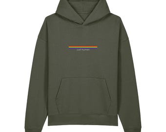 Könnte beinhalten: Ein olivgrüner Kapuzenpullover mit einer Kängurutasche auf der Vorderseite und langen Ärmeln. Mittig auf der Brust befindet sich eine horizontale Regenbogenstreifen-Grafik mit dem Text "just human" in kleinen weißen Buchstaben darunter.