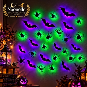 May include: A collection of black wall decals featuring silhouettes of bats, spiders, and spiderwebs. The decals are illuminated by vibrant green and purple LED backlighting, creating a glowing effect against the wall surface.