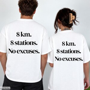 Könnte beinhalten: Zwei weiße kurzärmelige T-Shirts mit schwarzem Text auf der Rückseite, der 8 km. 8 stations. No excuses. lautet. Die T-Shirts haben einen Rundhalsausschnitt und eine Standardpassform und zeigen auf beiden Kleidungsstücken denselben Text.