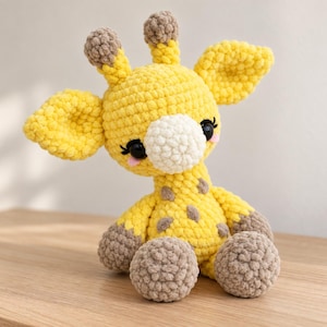 May include: A crochet giraffe plush toy made of bright yellow and light brown yarn. The stuffed animal features a white muzzle, two small horns, large ears, and black safety eyes with long eyelashes, accented by small pink circles under the eyes.