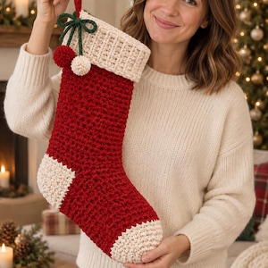 Peut inclure: Une chaussette de Noël crochetée avec un corps rouge profond, un revers côtelé couleur crème, ainsi qu'un talon et une pointe couleur crème. La chaussette est ornée d'un nœud en fil vert foncé et de deux petits pompons rouge et crème.