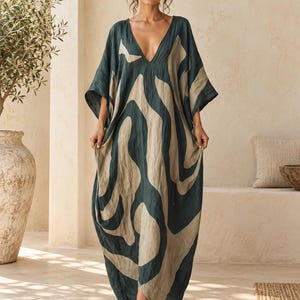 Könnte beinhalten: Ein bodenlanges Kaftan-Kleid mit tiefem V-Ausschnitt und weiten, lockeren Ärmeln. Das Kleidungsstück ist mit einem großflächigen, fließenden abstrakten Muster in Dunkelwaldgrün und hellem Beige verziert, das ein kühnes, durchgehendes Design bildet.