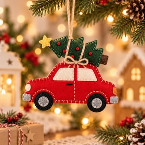 May include: A felt Christmas ornament shaped like a red car carrying a green Christmas tree on its roof. The car features white windows, black wheels with grey centers, and a small yellow star on the tree. It hangs from a brown twine string.