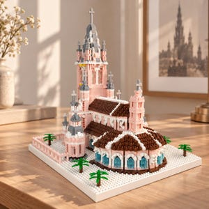 May include: A building model constructed from small plastic bricks featuring a tall central tower, brown tiled roofs, and light pink walls. The structure sits on a white base plate with small green palm trees and includes blue windows.